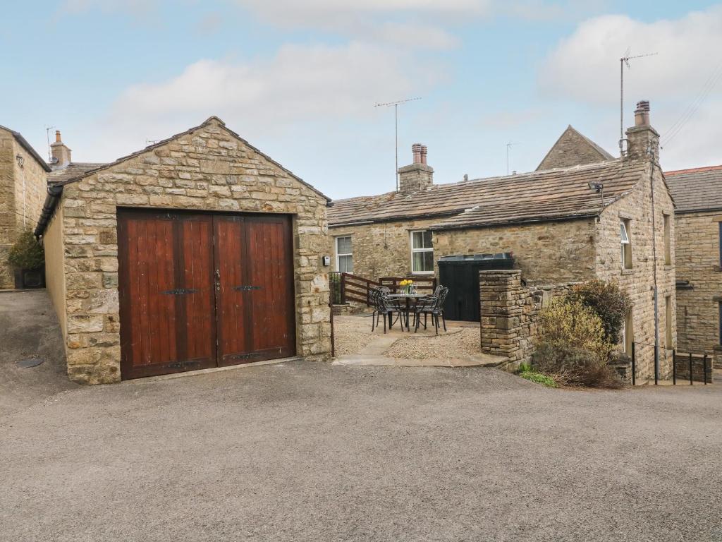 a stone house with a wooden garage and a table at Rockville in Hawes