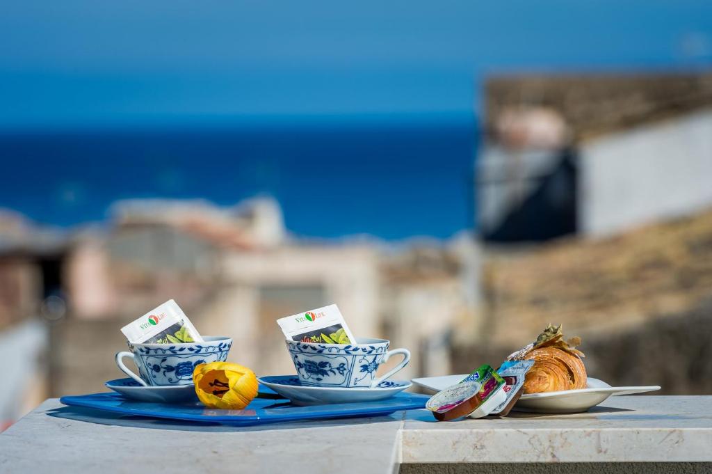 stół z dwoma kubkami i talerzami żywności w obiekcie Affittacamere Nanà w mieście Castellammare del Golfo