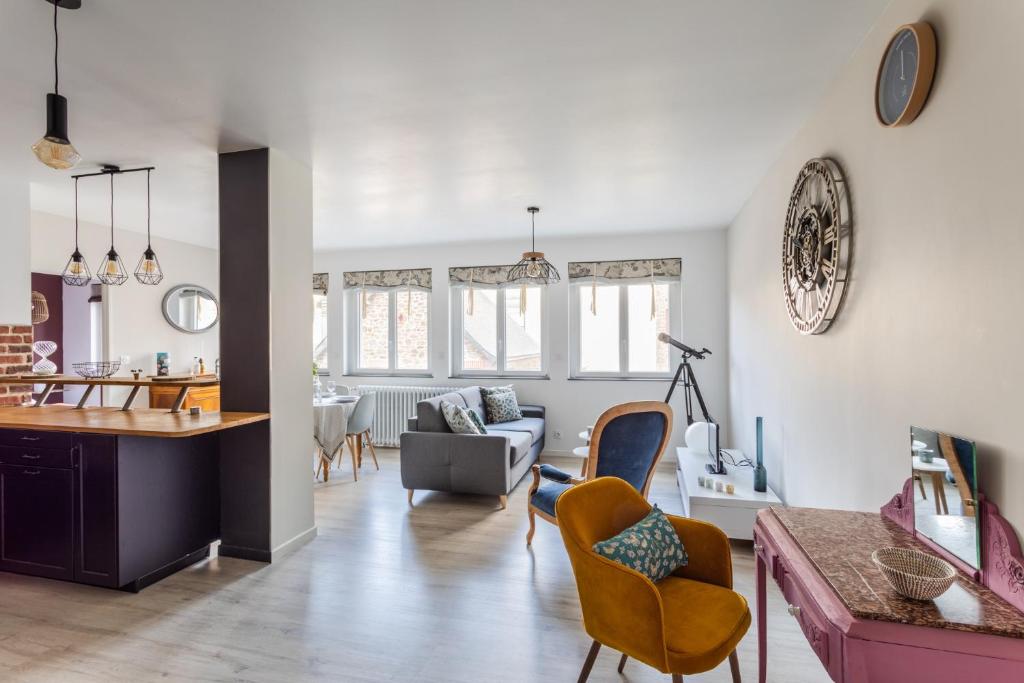 uma sala de estar com um sofá, uma mesa e cadeiras em Les Abîmes, beau logement avec 2 chambres avec parking em Saint Malo