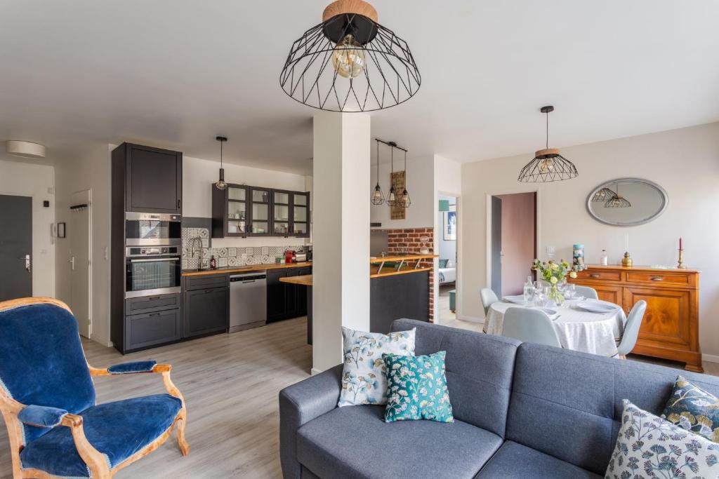 ein Wohnzimmer mit einem blauen Sofa und einer Küche in der Unterkunft Les Abîmes, beau logement avec 2 chambres avec parking in Saint-Malo