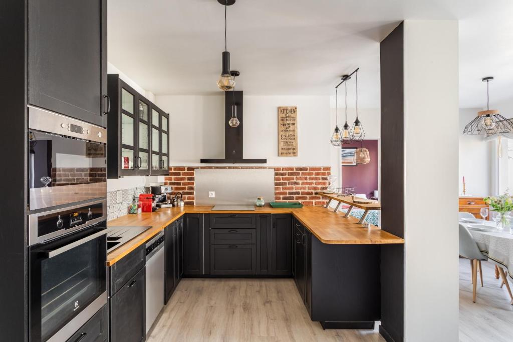 a kitchen with black cabinets and a wooden counter top at Les Abîmes, beau logement avec 2 chambres avec parking in Saint Malo