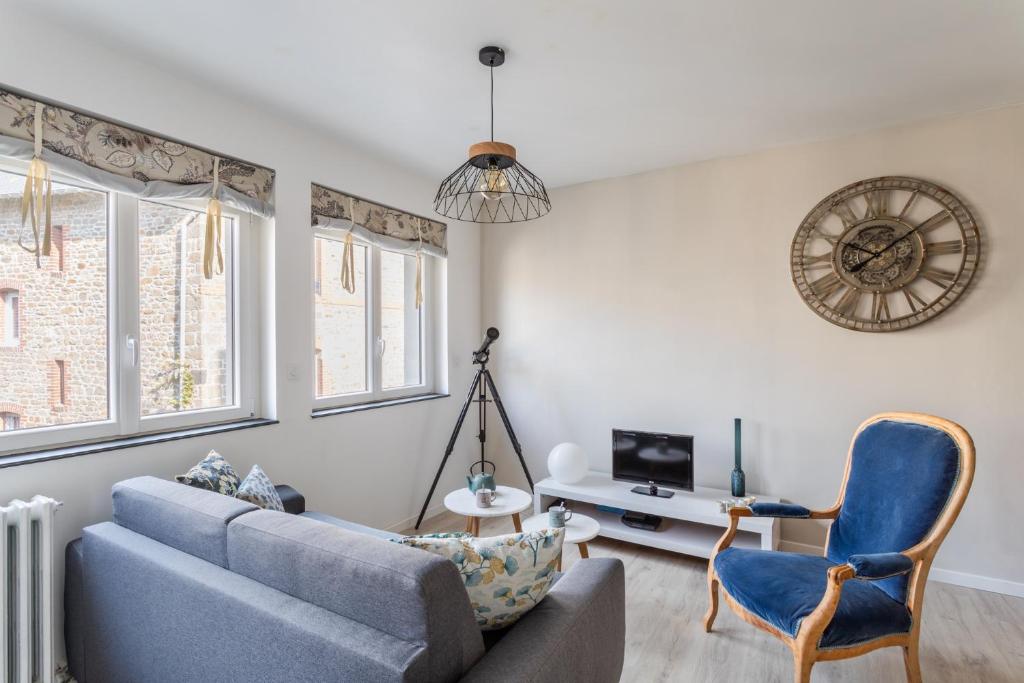 ein Wohnzimmer mit einem blauen Sofa und einem Stuhl in der Unterkunft Les Abîmes, beau logement avec 2 chambres avec parking in Saint-Malo