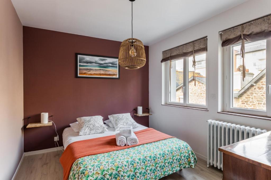ein Schlafzimmer mit einem Bett und zwei Fenstern in der Unterkunft Les Abîmes, beau logement avec 2 chambres avec parking in Saint-Malo