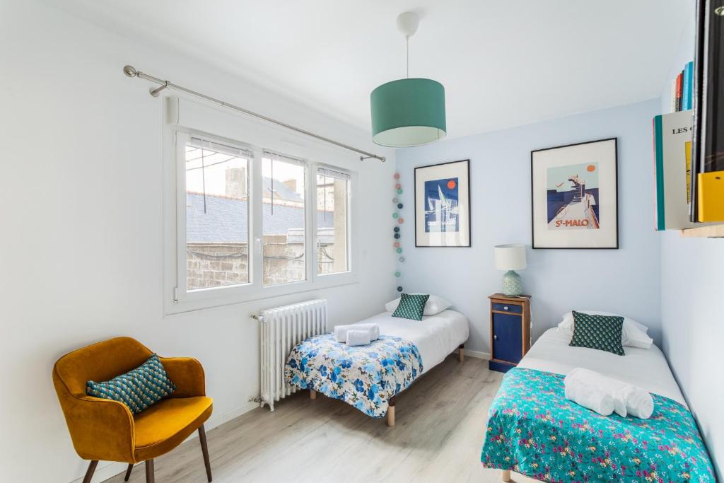1 Schlafzimmer mit 2 Betten und einem Stuhl in der Unterkunft Les Abîmes, beau logement avec 2 chambres avec parking in Saint-Malo