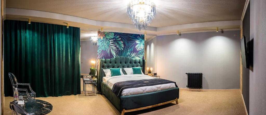 a bedroom with a bed with green curtains and a chandelier at RICH Boutique-Hotel in Vinnytsya