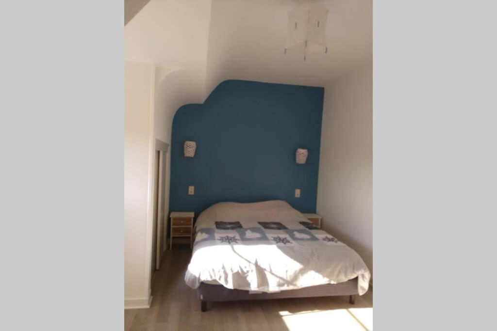um quarto com uma cama com uma cabeceira azul em 12 2et avec jardin 4-5per Les Gites Bigoudens 10 mn plages em Plonéour-Lanvern