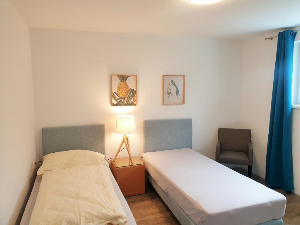 a bedroom with two beds and a lamp and a chair at Aparthotel Kreuzwirt in Engerwitzdorf