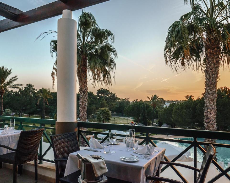 a restaurant with tables and chairs and palm trees at Vale d'El Rei Hotel & Villas in Carvoeiro
