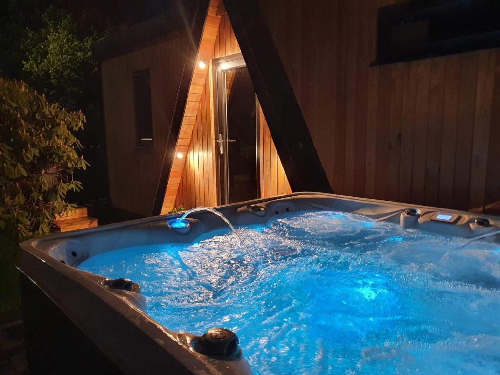 a jacuzzi tub in a backyard at night at Little Woodbine in Tain