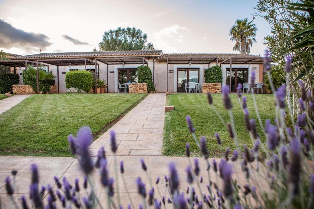 a garden with purple flowers in front of a house at Agroturismo Can Pere Rei in Son Serra de Marina