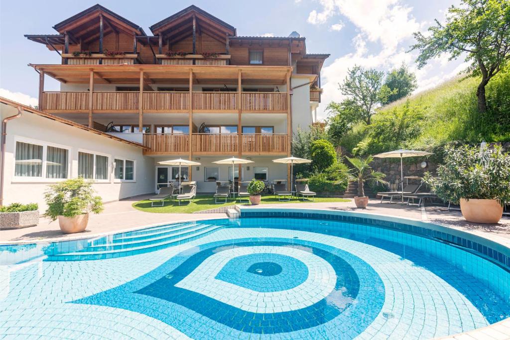 a house with a swimming pool in front of a building at Wanderhotel Teiserhof in Funes