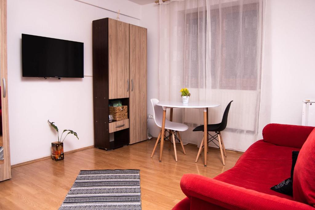 - un salon avec un canapé rouge et une table dans l'établissement Butterfly Apartment-Hidden Gem in the Heart of Targu Mures, à Târgu-Mureş