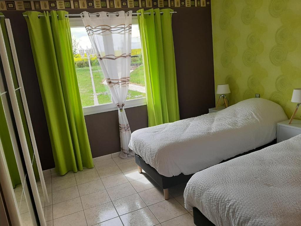 a bedroom with two beds and a window with green curtains at Les lits de la Py in Sommepy-Tahure