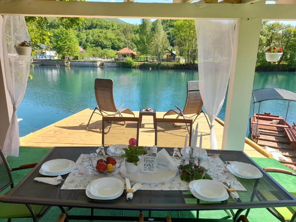 a table with plates of food on a patio with a view of the water at Una Luxury Home in Bihać