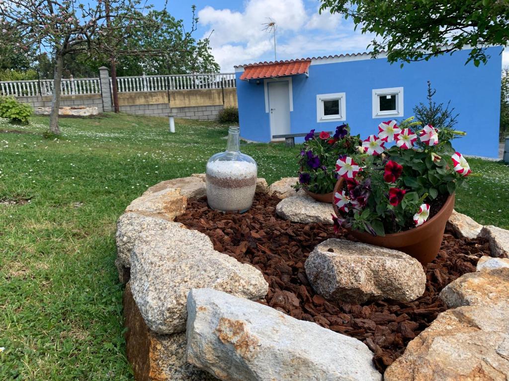un jardín con rocas y flores y una casa azul en Casa rural La casilla de Ois-Betanzos-A Coruña, en Coirós