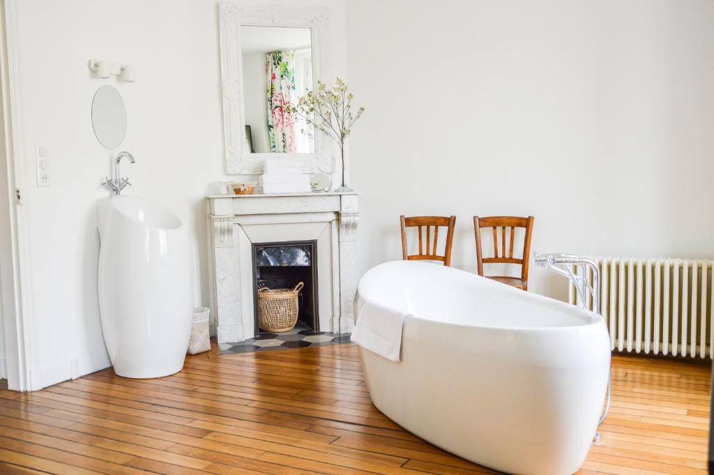 - une baignoire blanche dans une pièce avec cheminée dans l'établissement Les Berceaux de la Cathedrale, à Reims