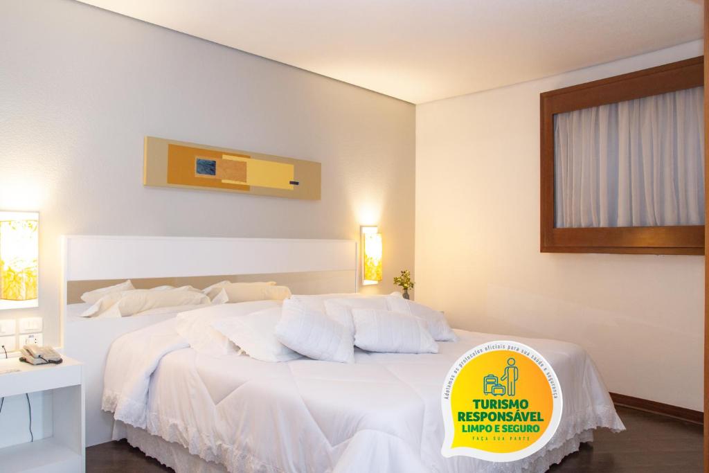 ein weißes Schlafzimmer mit einem großen Bett mit weißen Kissen in der Unterkunft Bristol Brasil 500 Curitiba Batel in Curitiba