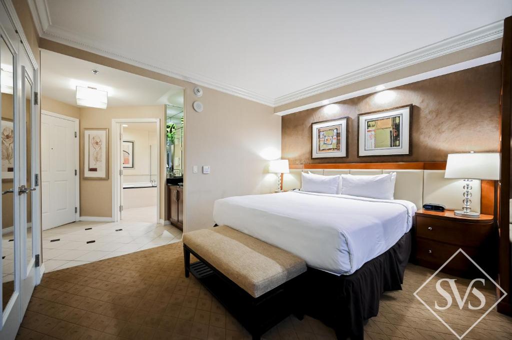 a bedroom with a large white bed and a chair at StripViewSuites at Signature in Las Vegas