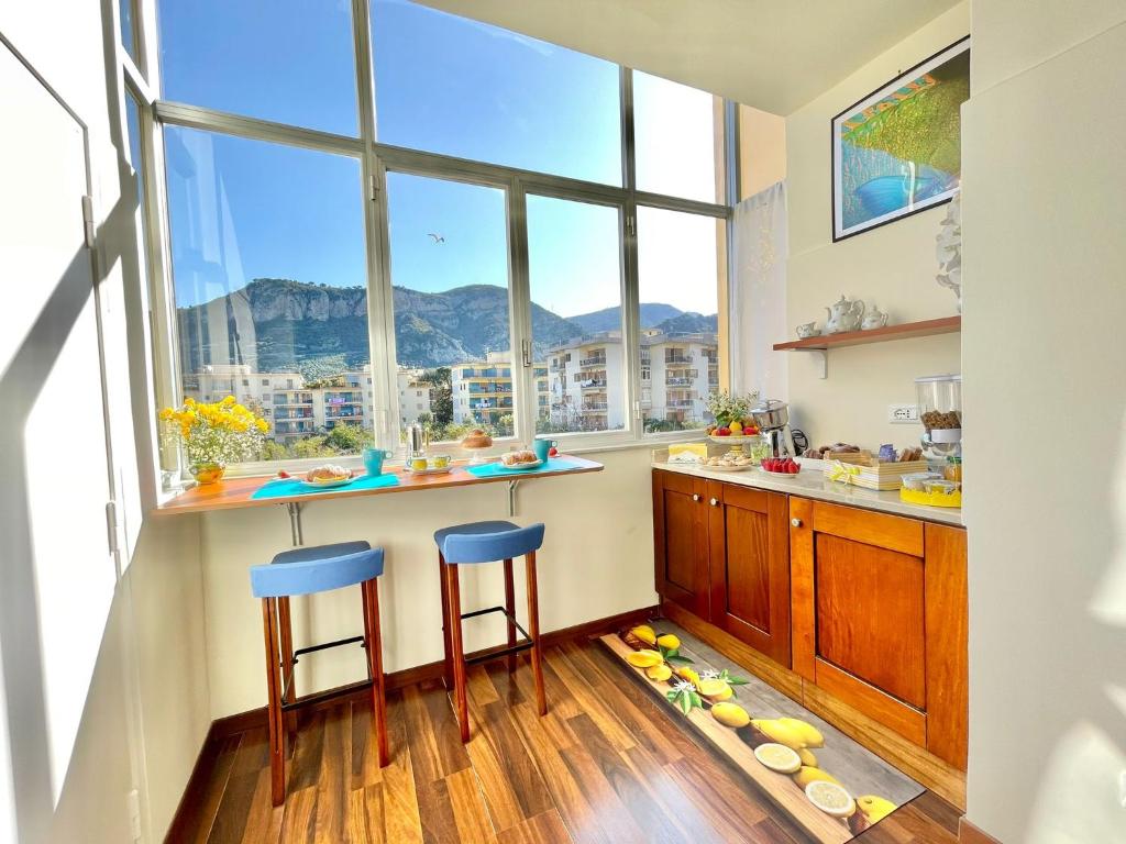 a kitchen with two stools and a counter with windows at B&B Tina in Piano di Sorrento