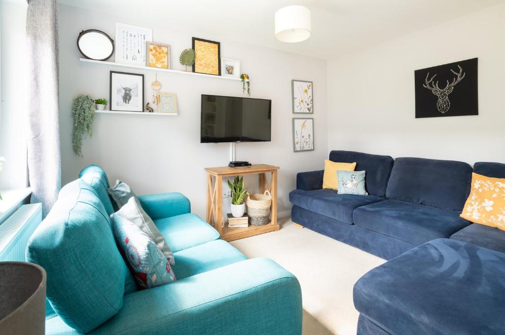 ein Wohnzimmer mit blauen Sofas und einem TV in der Unterkunft Lily Bank House in Inverness