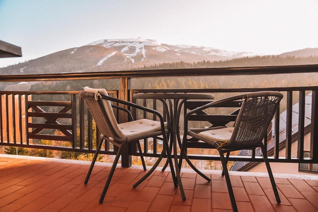 two chairs and a table on a balcony with a snow covered mountain at Apartment Bjelasnica in Bjelašnica