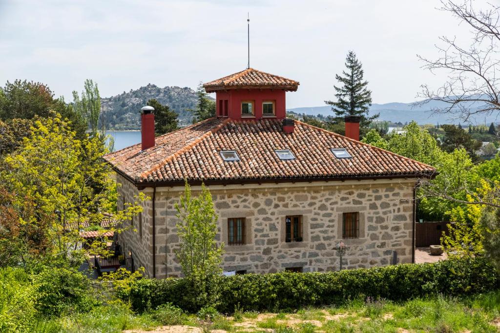 una antigua casa de piedra con techo rojo en El Torreon de Navacerrada, en Navacerrada