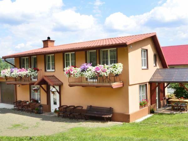 a house with flowers on the balcony with a bench at Pokoje Gościnne Sonea in Lewin Kłodzki