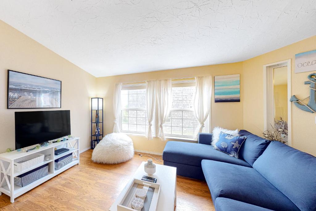 een woonkamer met een blauwe bank en een tv bij Lighthouse View in Lincoln City