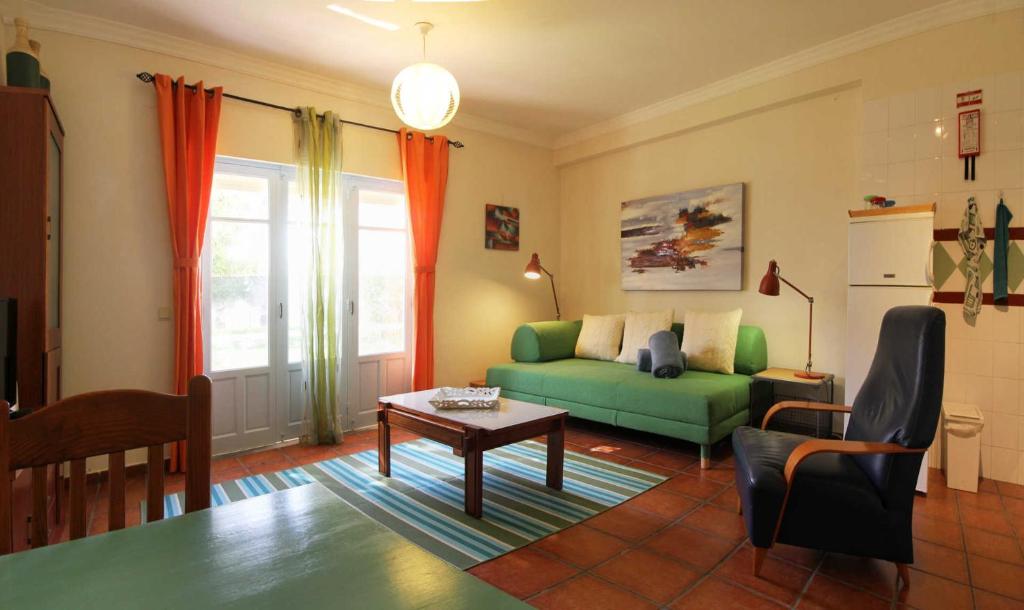 Una sala de estar con un sofá verde y una mesa. en Apartamento Azur, en Vila Nova de Milfontes