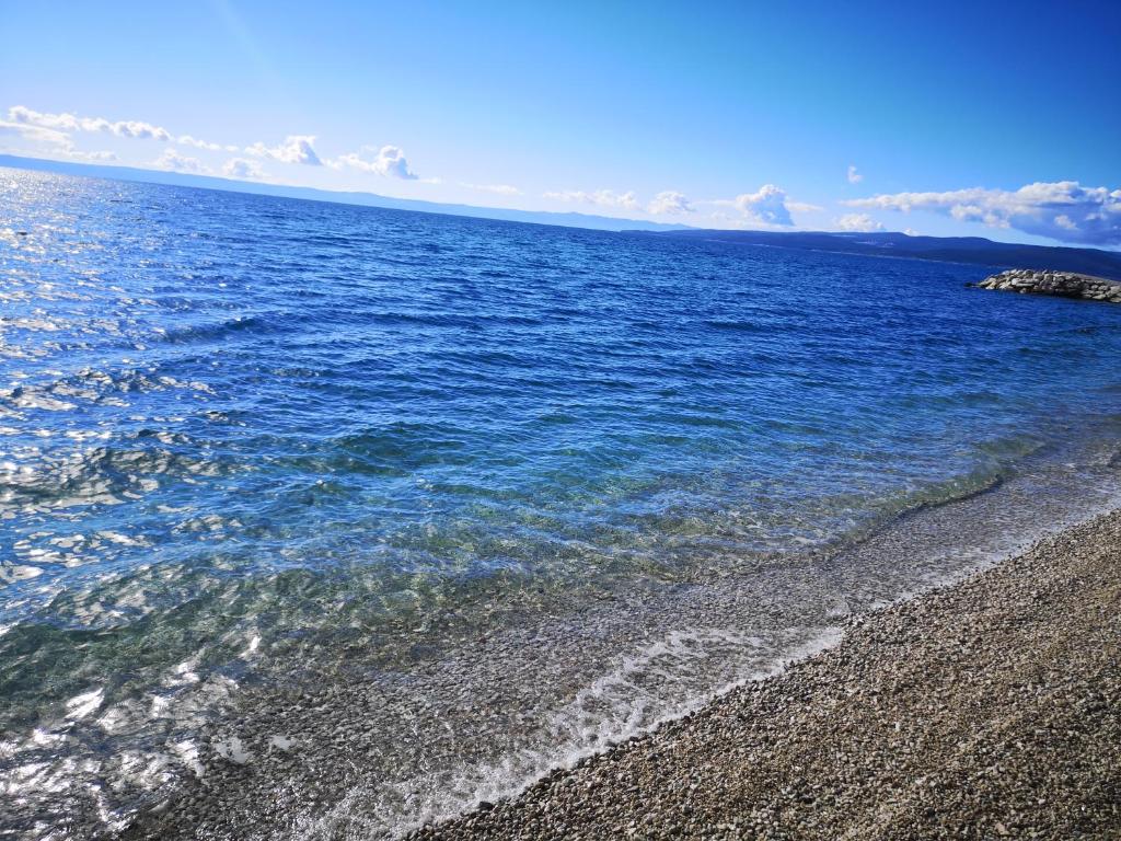 a beach with blue water and a rocky shore at Villa Šutić in Promajna