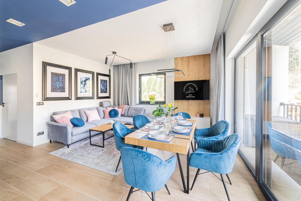 uma sala de estar com uma mesa e cadeiras azuis em Apartament Nad Potokiem Skrzyczne Residence em Szczyrk
