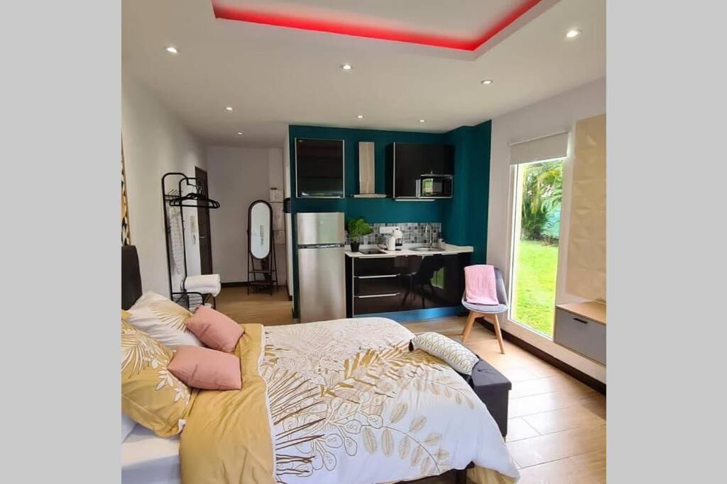 een slaapkamer met een bed en een keuken met een tafel bij Studio chic et cosy in Cayenne