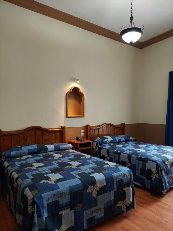 a bedroom with two beds with blue comforters at Hotel De Talavera in Puebla