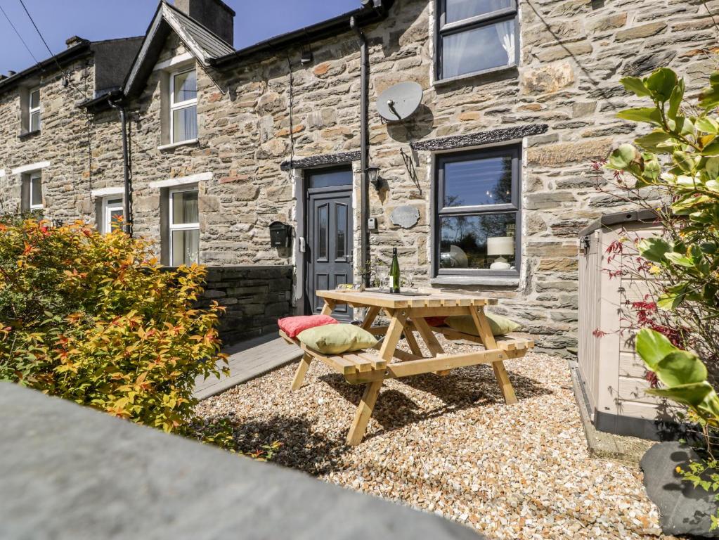 a wooden picnic table in front of a stone cottage at Bwthyn Afon River Cottage in Blaenau-Ffestiniog