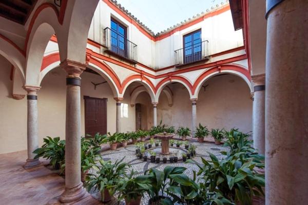 un gran edificio con un patio con plantas. en La Puerta Azul, en Bornos