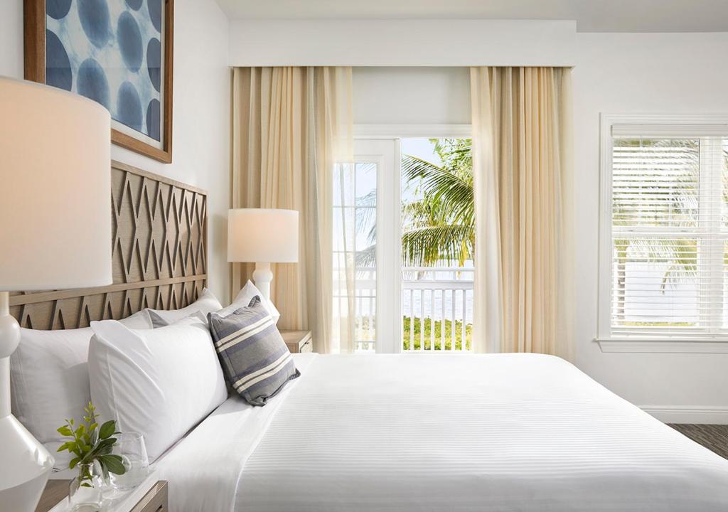 ein weißes Schlafzimmer mit einem großen Bett und einem Fenster in der Unterkunft Parrot Key Hotel &amp; Villas in Key West