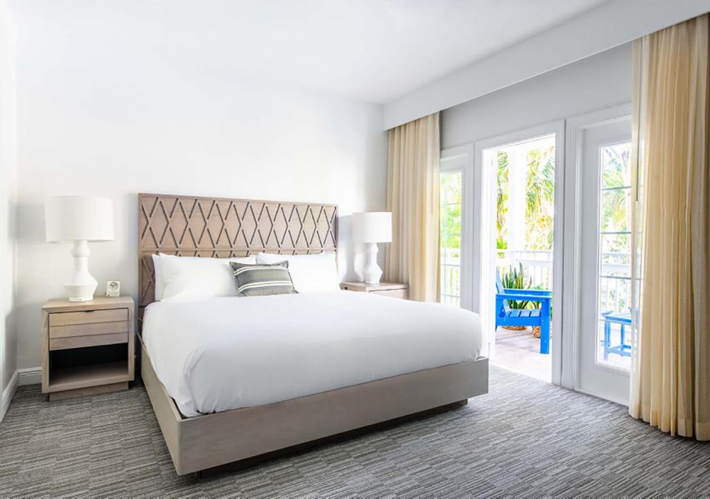 ein Schlafzimmer mit einem weißen Bett und einer Glasschiebetür in der Unterkunft Parrot Key Hotel &amp; Villas in Key West