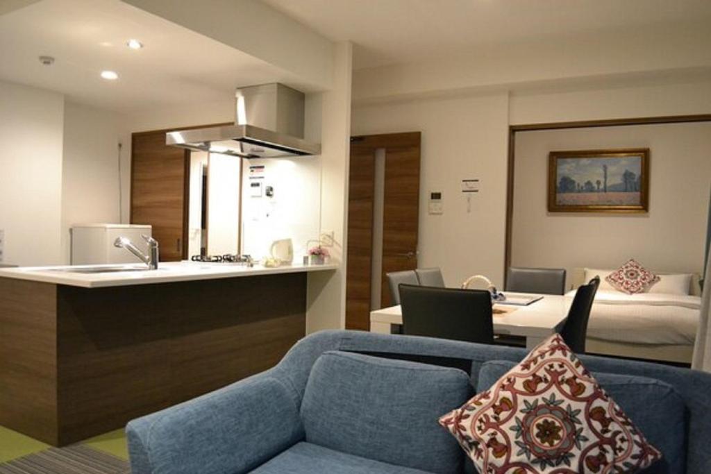uma sala de estar com um sofá azul e uma cozinha em A,T,HOTEL HAKATA - Vacation STAY 36414v em Fukuoka