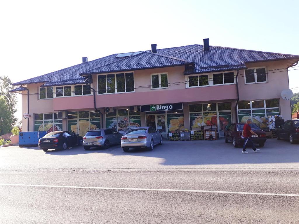 un gran edificio con coches estacionados en un estacionamiento en Private Home Rifat en Dubrave Gornje