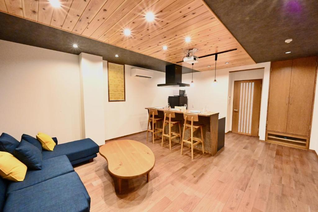 a living room with a blue couch and a table at Manabi-stay Takayama SAKURA 提携駐車場利用可 古い町並みまで徒歩1分 最大9名宿泊可能な一等地で人工温泉を楽しむ in Takayama