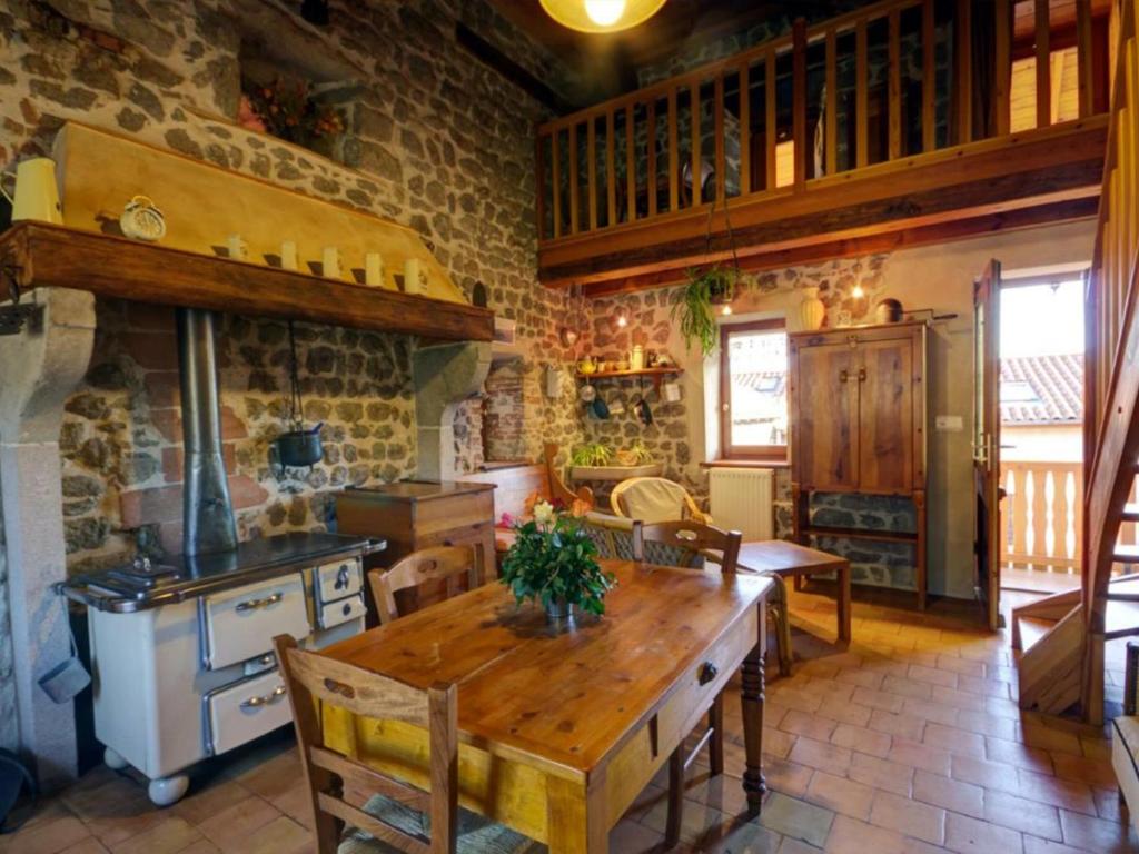 a kitchen with a wooden table and a stone wall at Gîte Essertines-en-Châtelneuf, 3 pièces, 6 personnes - FR-1-496-16 in Essertines-en-Châtelneuf