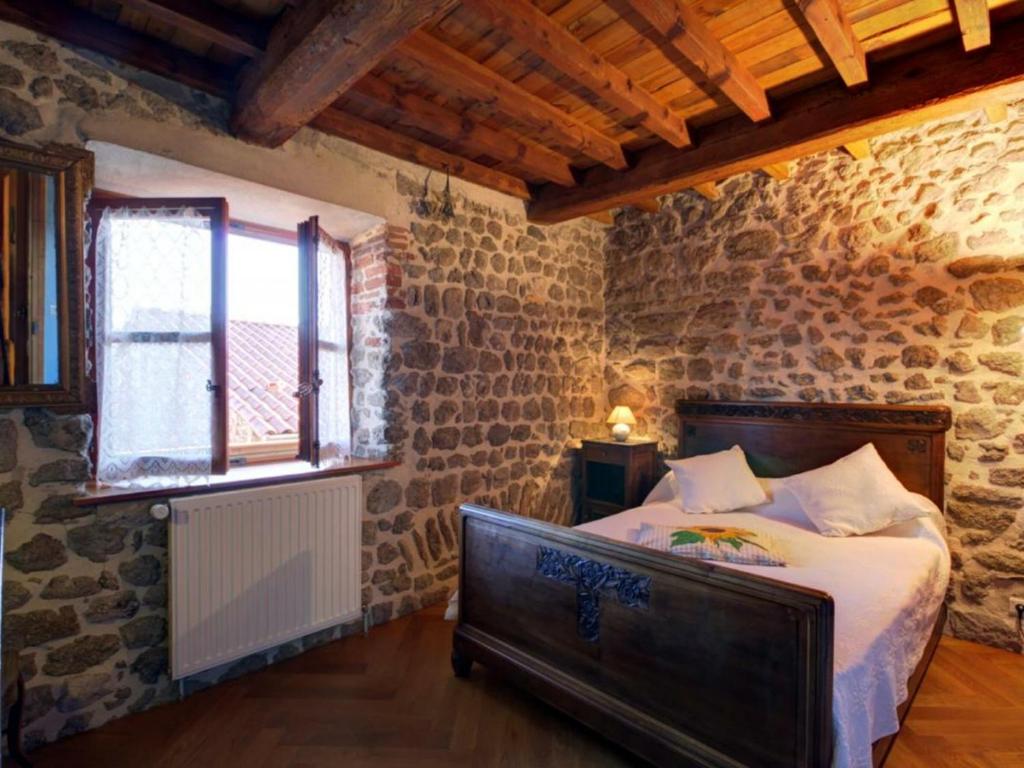 a bedroom with a bed in a room with stone walls at Gîte Essertines-en-Châtelneuf, 3 pièces, 6 personnes - FR-1-496-16 in Essertines-en-Châtelneuf