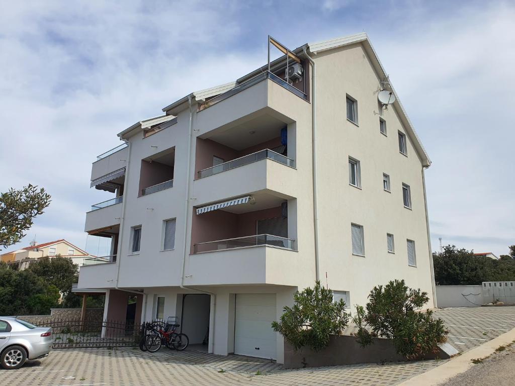 a tall white building with a parking lot at Apartma Šelih Mandre - Pag in Mandre