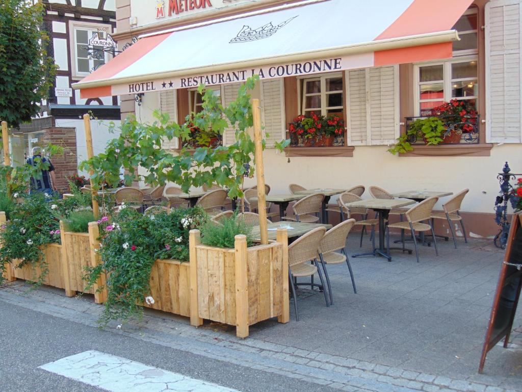 um restaurante com mesas e cadeiras e plantas no passeio em La Couronne à Wissembourg em Wissembourg