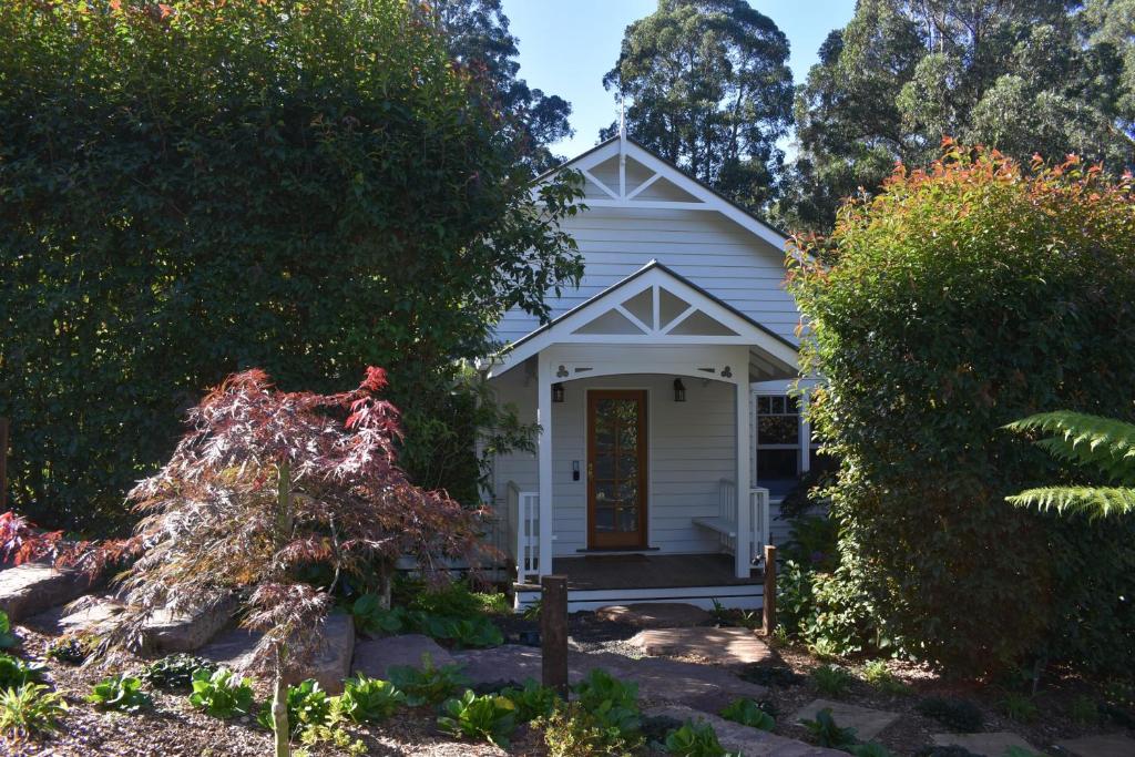 a small white house with a red door at Fern Falls Cottages - Garden Cottage in Mount Dandenong