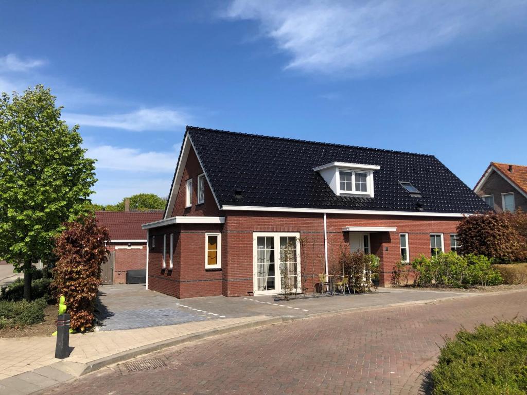 a red brick house with a black roof at Etoile aan Zee in Vrouwenpolder