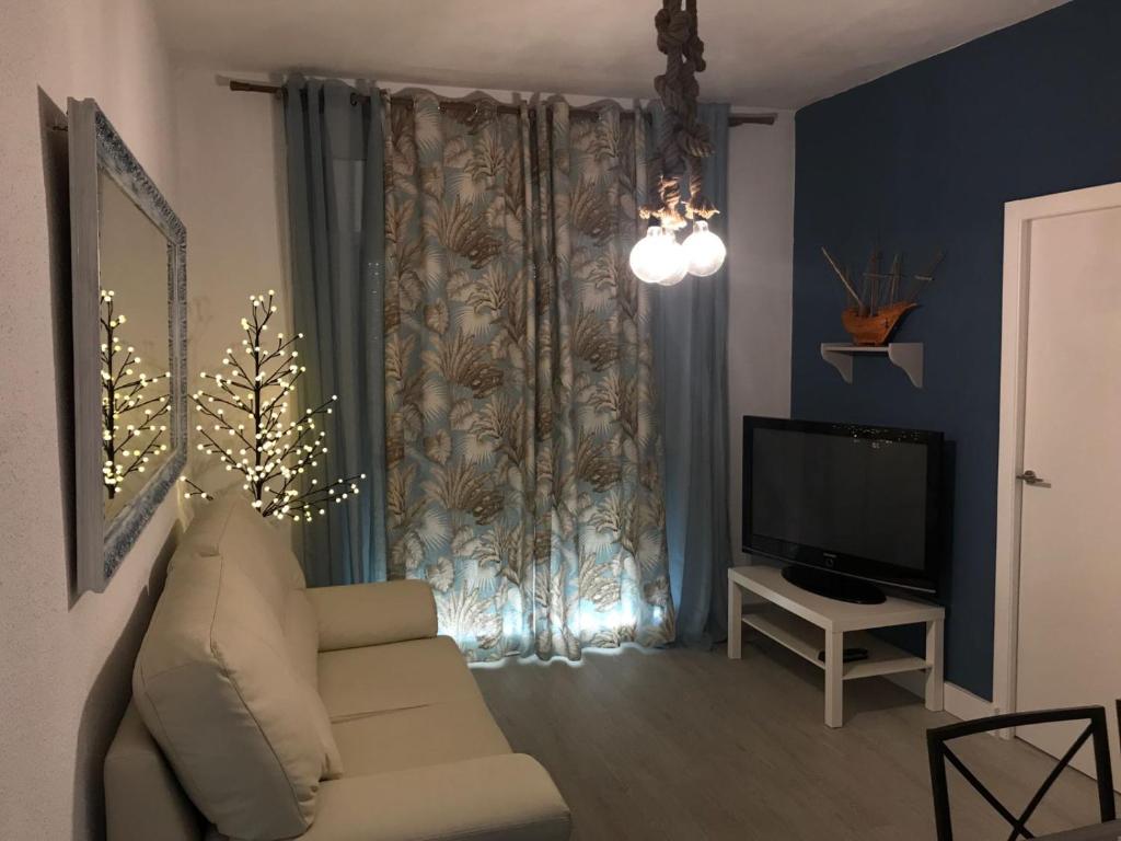 een woonkamer met een bank en een televisie bij Océano Home in Ayamonte