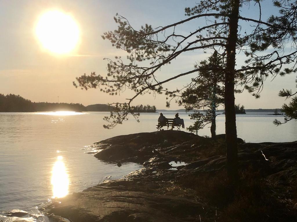 a person sitting on a bench next to a lake at Casino Islands Getaway in Savonlinna
