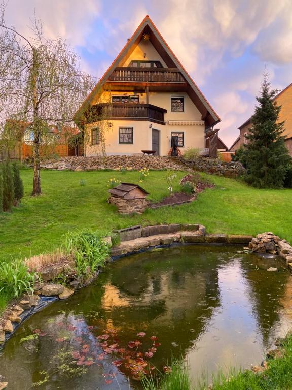 une maison avec un étang en face de celle-ci dans l'établissement Ferienwohnung "Grünes Tor" bei Dresden, à Dohna