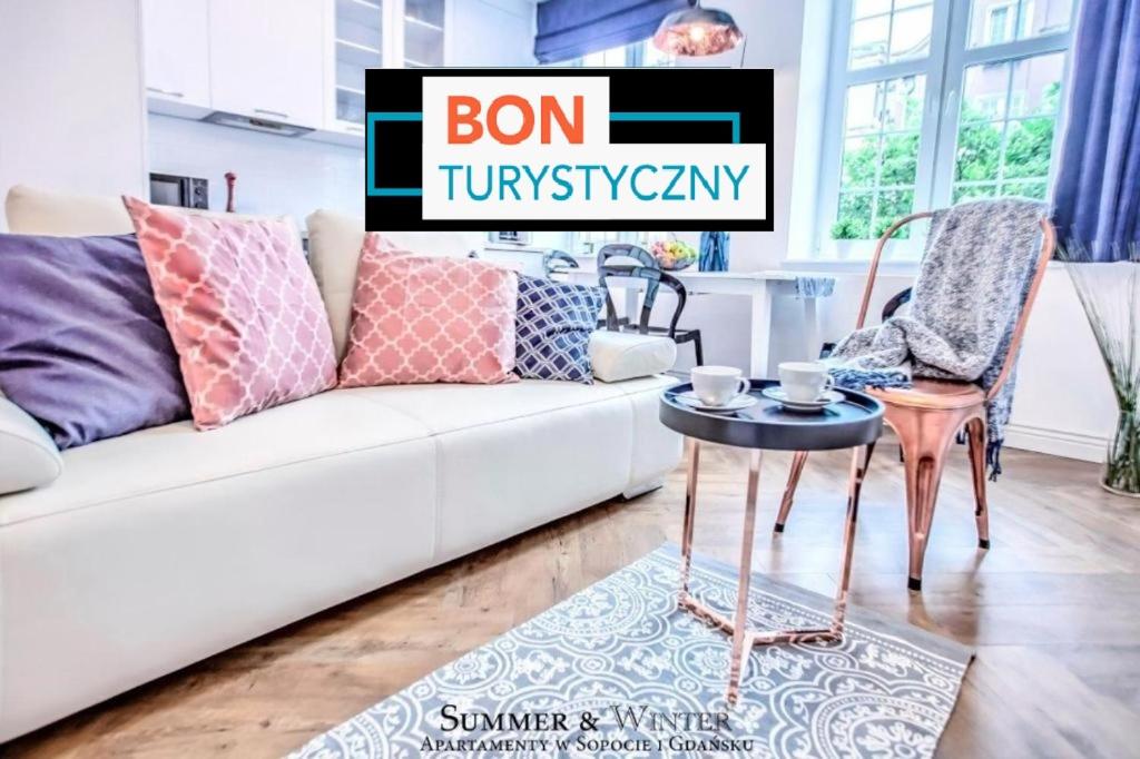 a living room with a white couch and a table at Family Luxury Nature Apartment, 1-6, 2 sypialnie i salon, 100m Bazylika in Gdańsk